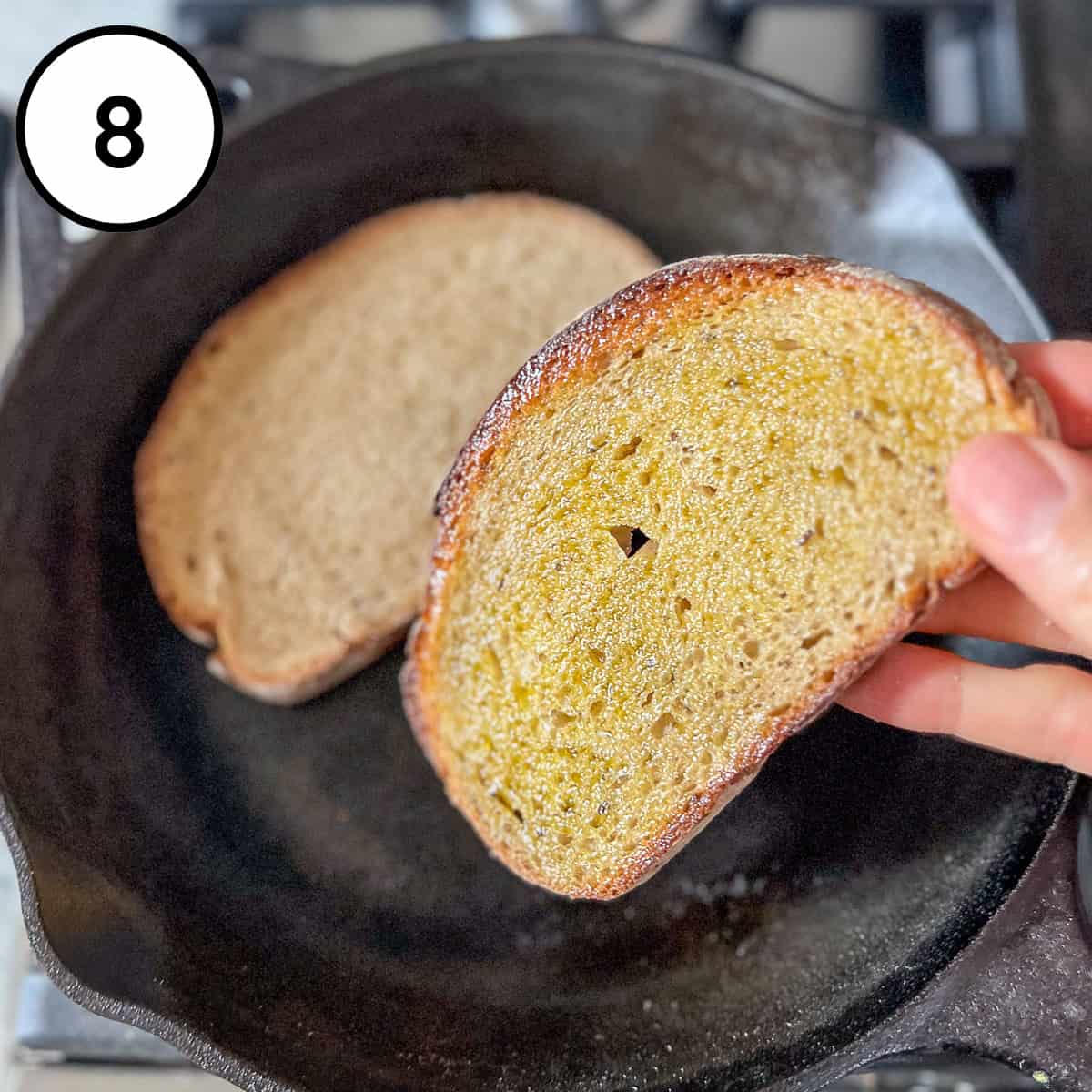 Bread being toasted in cast iron skillet.