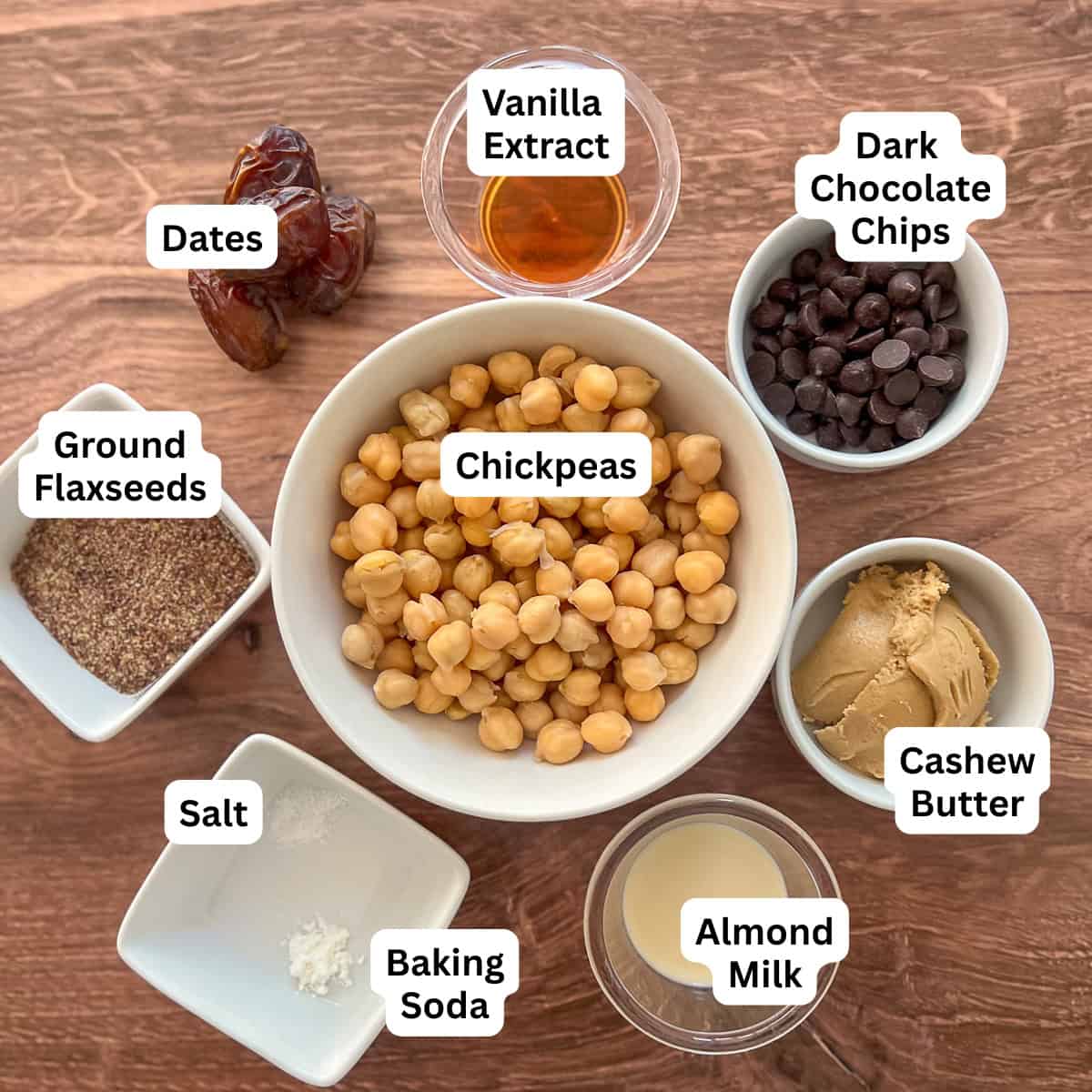 Ingredients for vegan cookie dough: chickpeas, ground flaxseeds, dark chocolate chips, vanilla extract, dates, cashew butter, almond milk, salt, and baking soda.