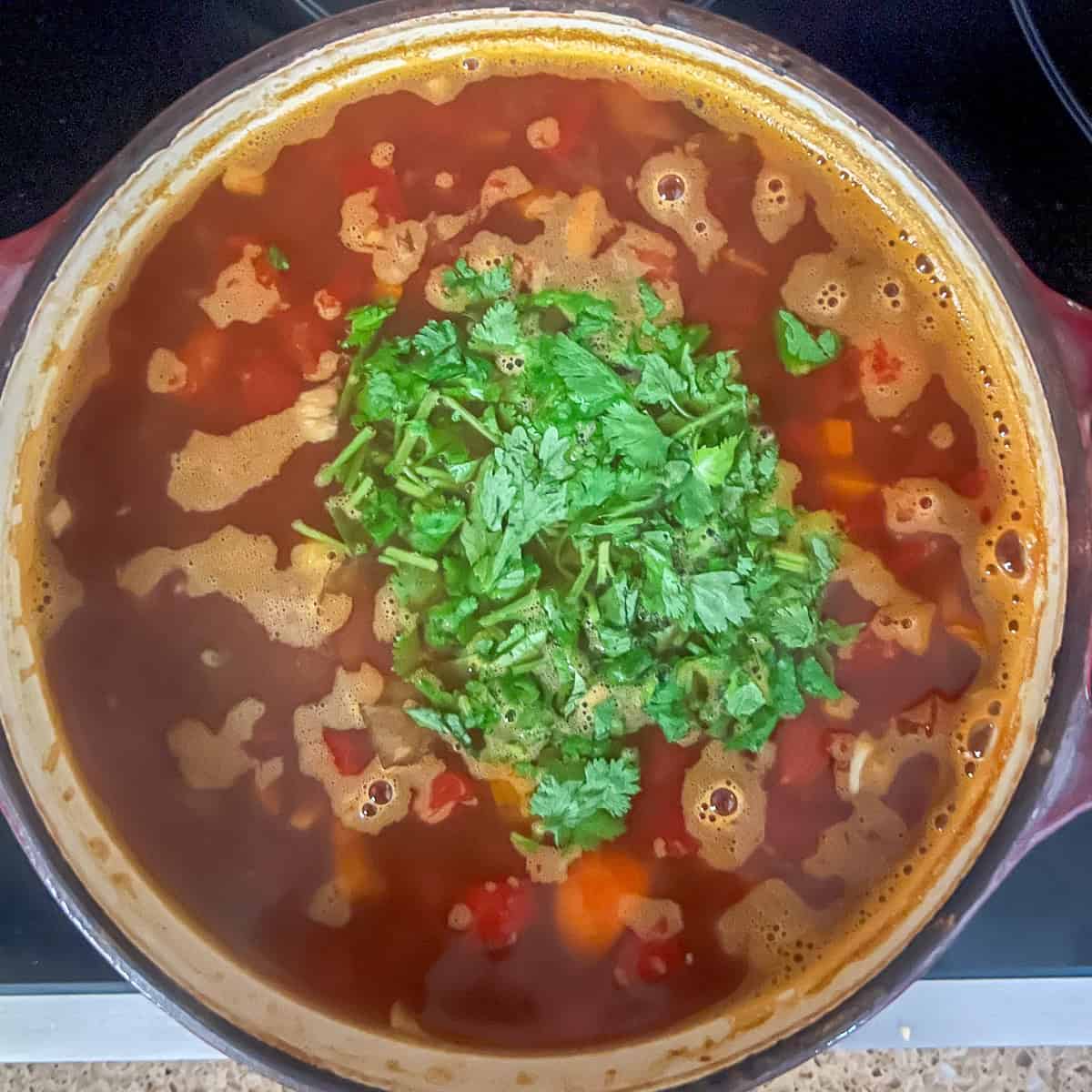 Fresh chopped cilantro added to the pot of black bean tortilla soup.