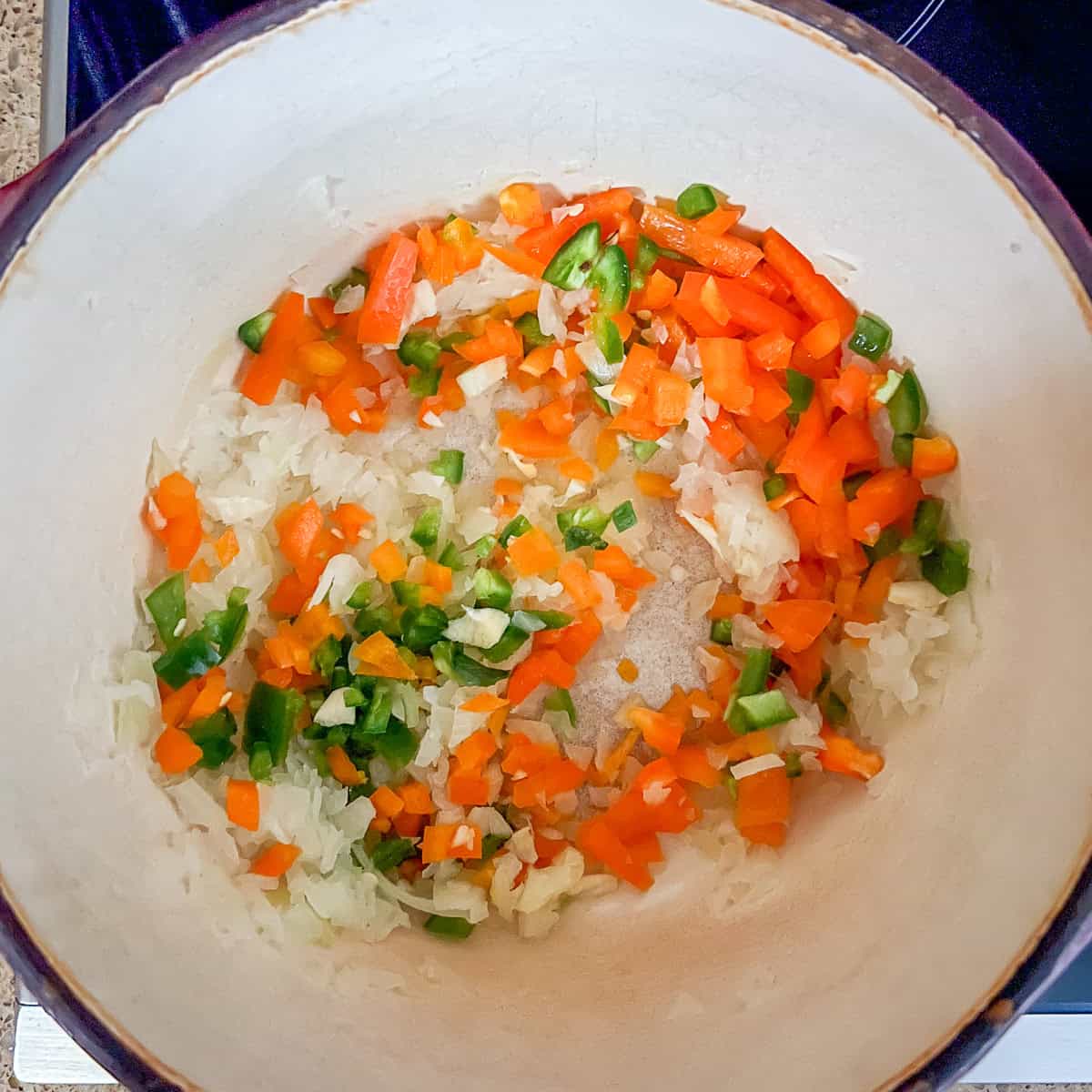 Chopped veggies sauteing in a large pot.