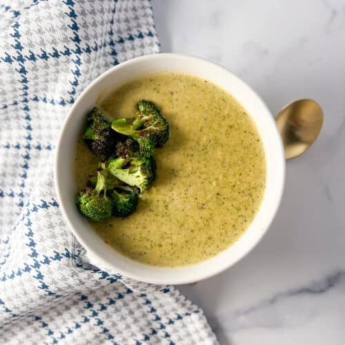 Vegan cream of broccoli soup in a bowl with a spoon on the side.