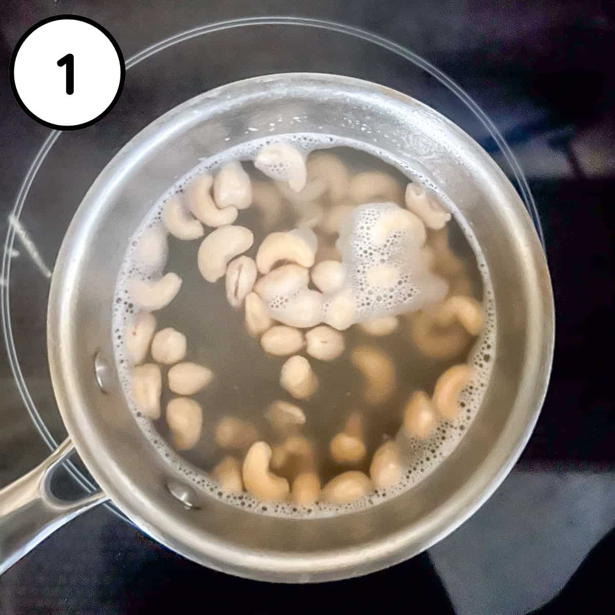 Cashews being gently boiled in a pot of water.