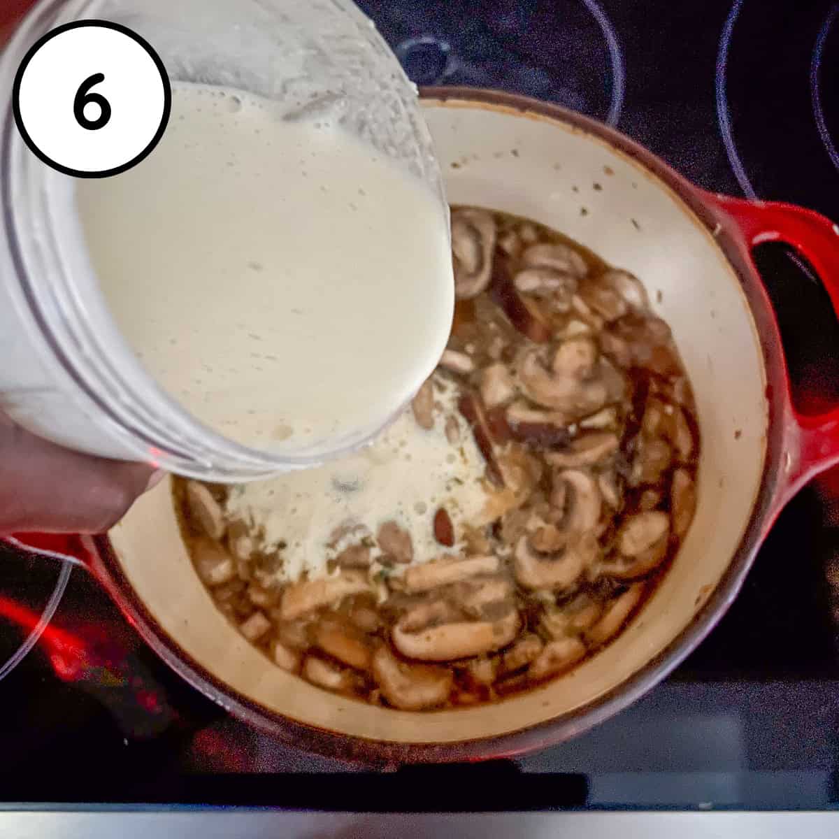 Cream sauce being added to the pot with mushrooms and broth.