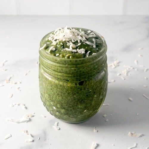 Matcha chia pudding in a small jar topped with shredded coconut.