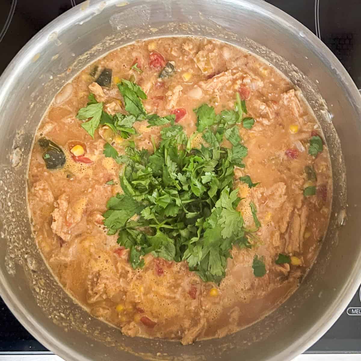 Fresh chopped cilantro added to the pot of vegan chicken tortilla soup.