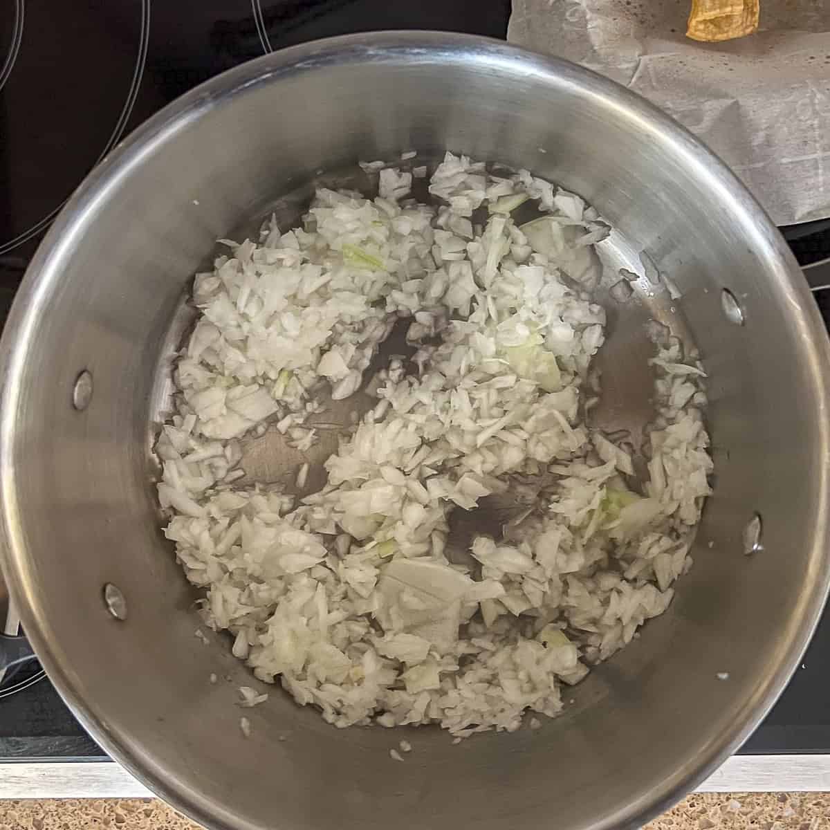 Chopped onion sauteing in a pot on the stovetop.