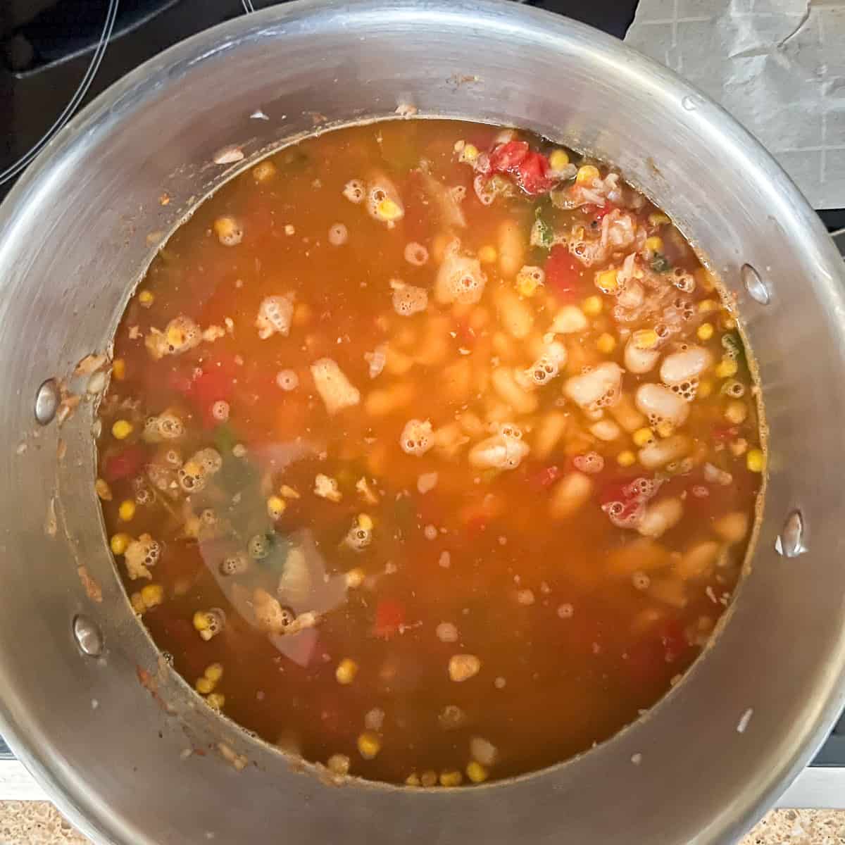 Vegetables, beans and broth in the pot on the stovetop.