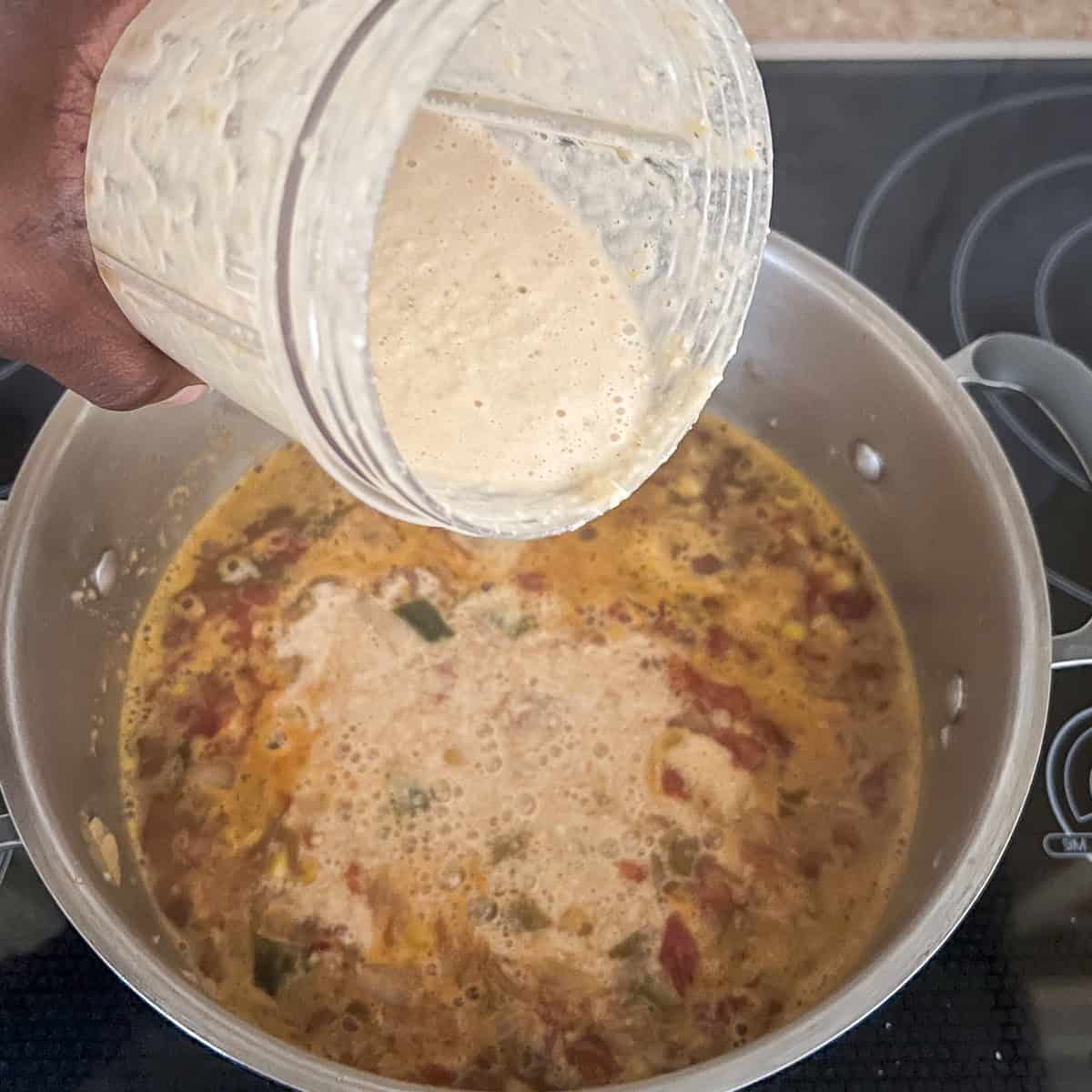 Cream mixture being poured back into the soup pot.