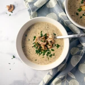 A bowl of vegan cream of mushroom soup with a spoon.
