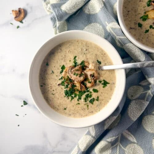A bowl of vegan cream of mushroom soup with a spoon.