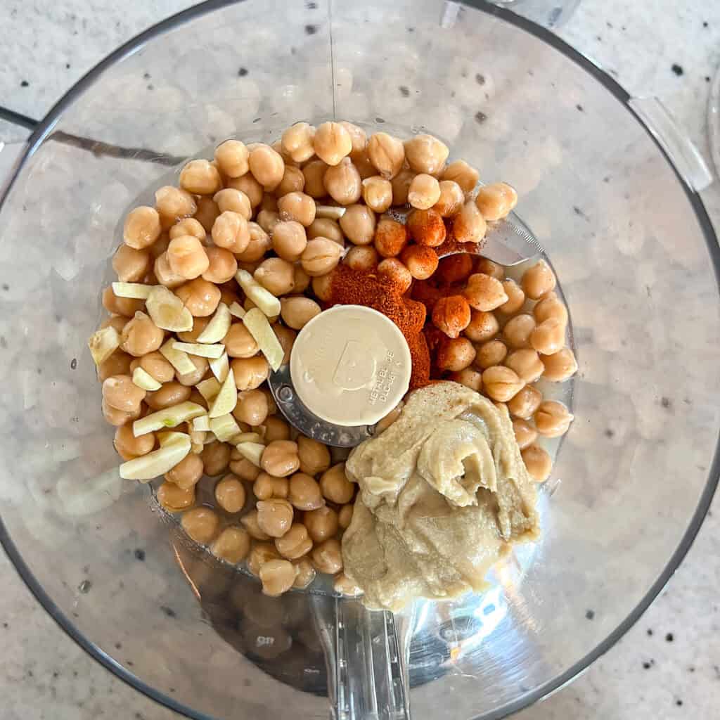 Ingredients for harissa hummus in a food processor before processing.