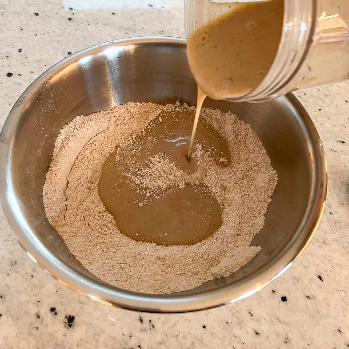 The vegan eggnog mixture being added to dry ingredients.