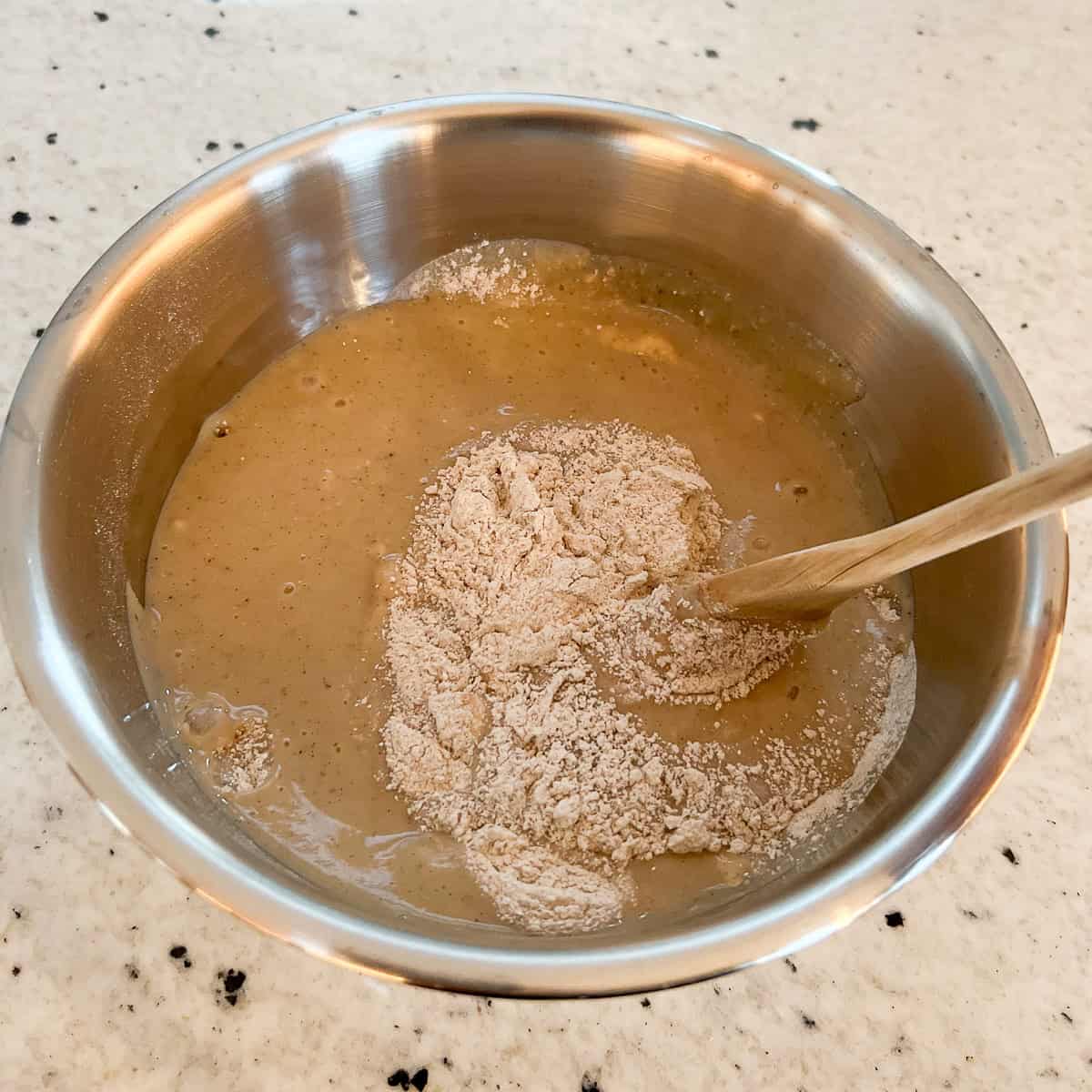 Vegan eggnog batter being combined with a wooden spoon.