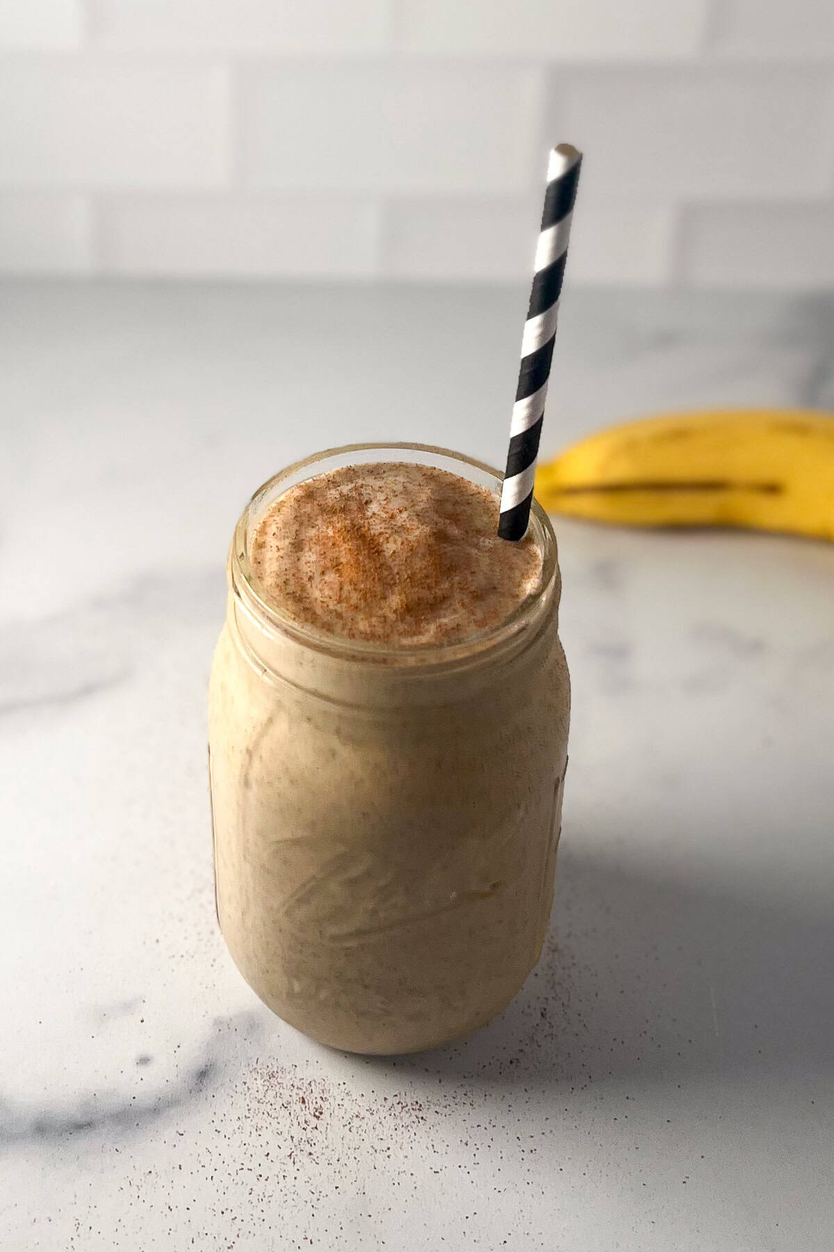 Chia banana peanut butter smoothie in a mason jar with a straw.