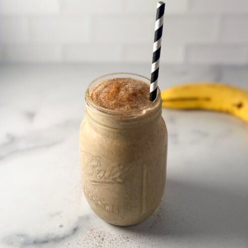 Peanut butter chia seed smoothie in a mason jar with banana in the background.