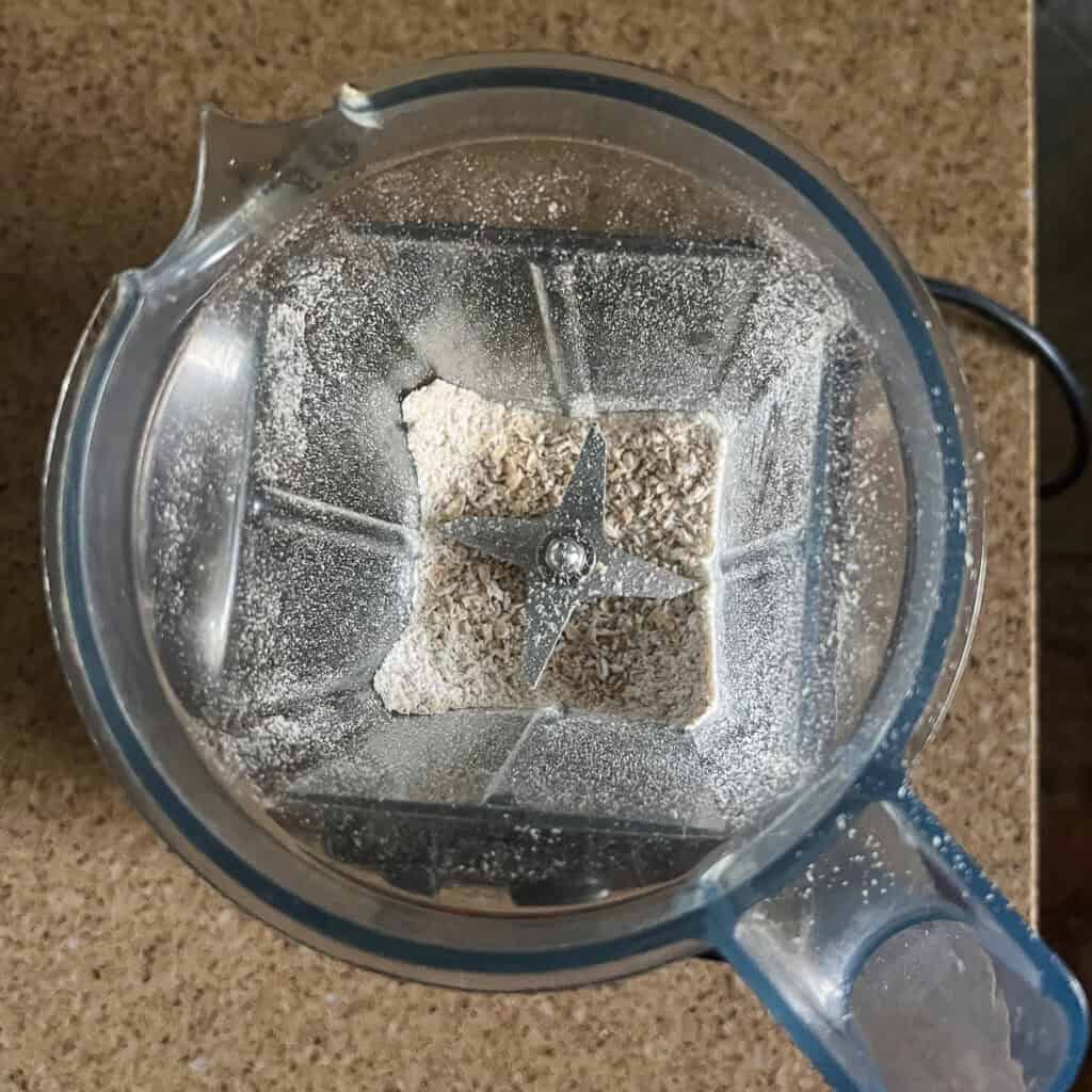 Rolled oats in a blender pitcher after being blended into a powder.