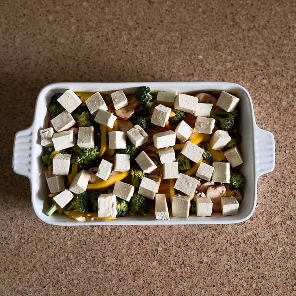 Tofu chunks added to the casserole dish with other ingredients.