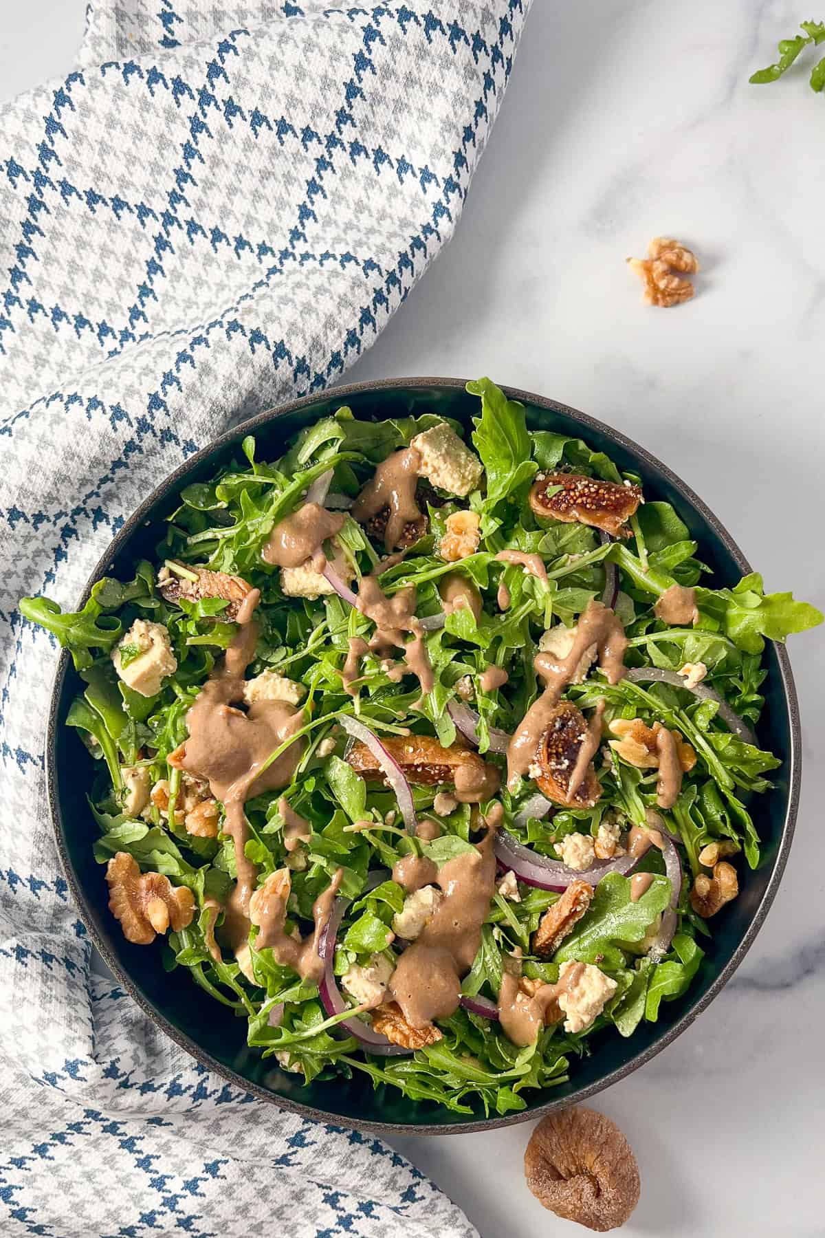 Arugula fig and walnut salad in a bowl with a napkin on the side.