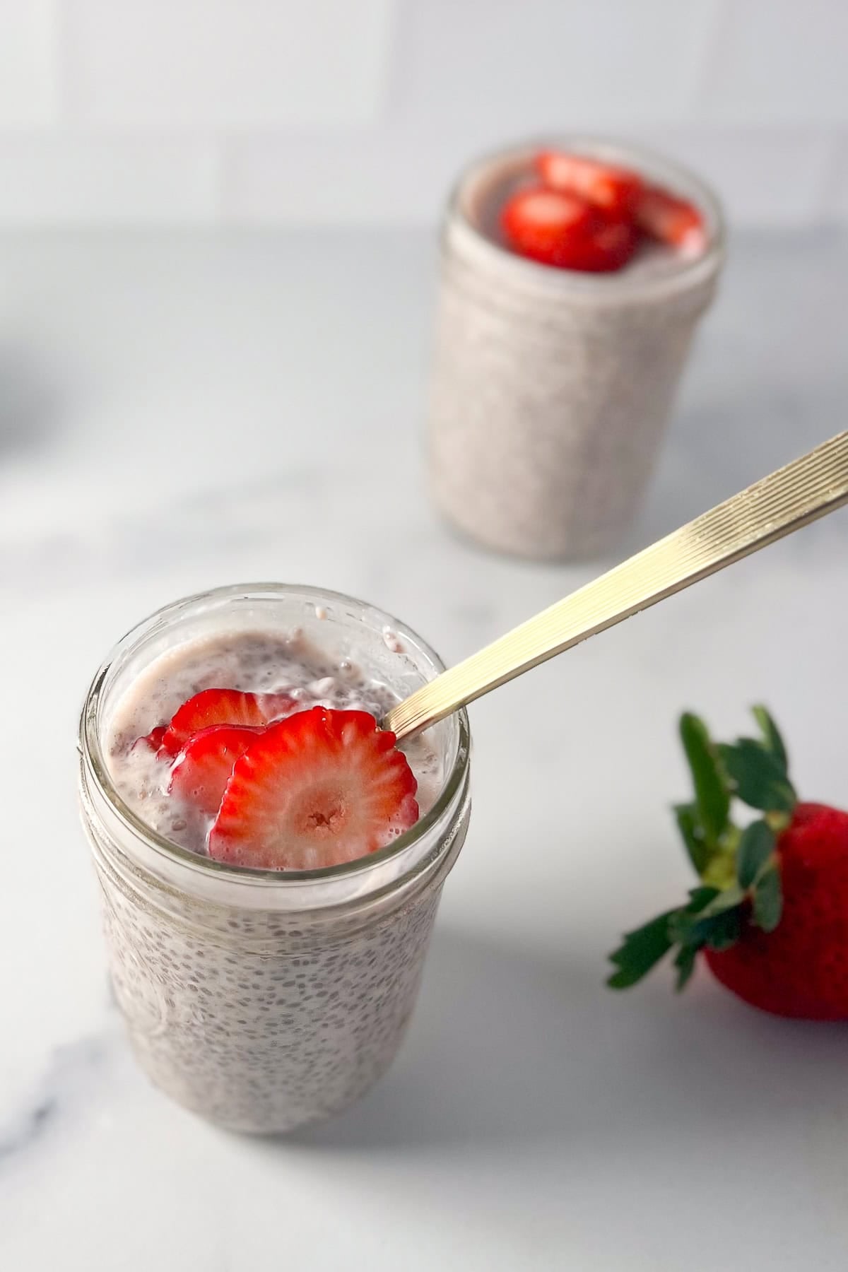 Chia Strawberry Pudding in a mason jar with a spoon.