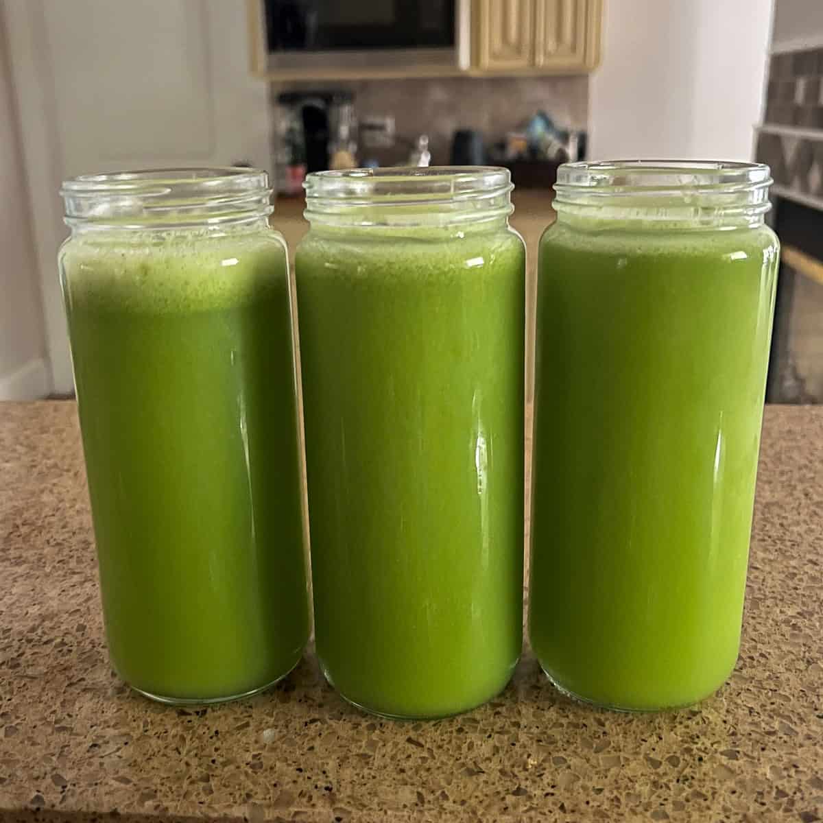 Three celery cucumber juices in tall mason jar glasses.
