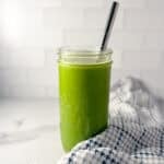 Celery cucumber juice in a tall glass with a metal straw.