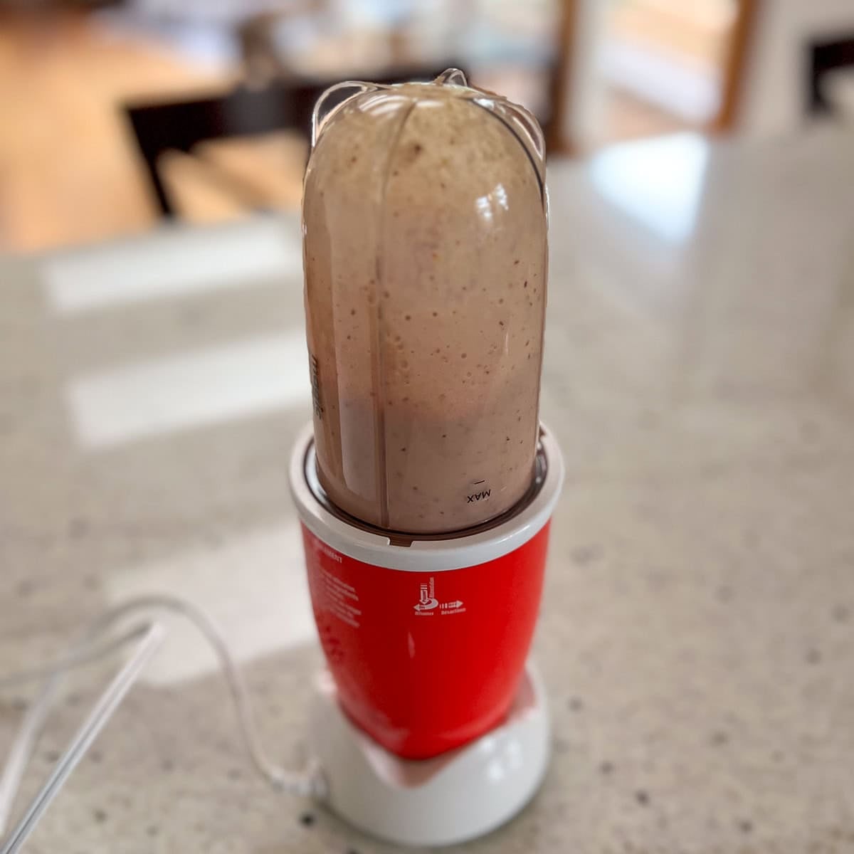 Peach milk mixture being blended in a bullet blender.