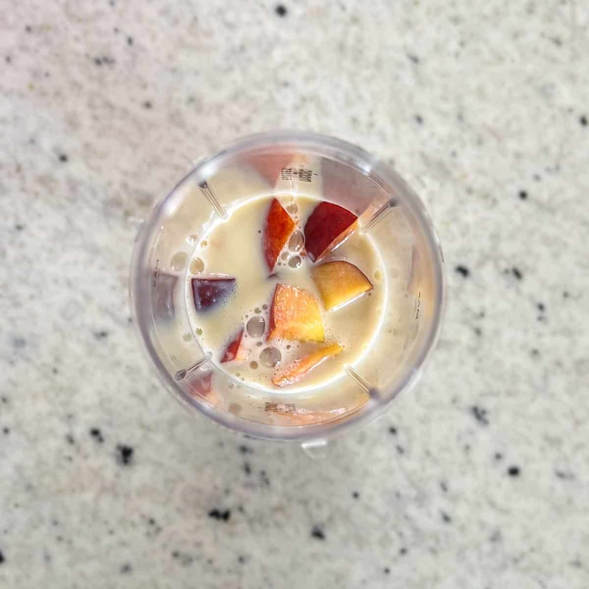 Peaches, half of the soy milk and maple syrup in a blender cup.