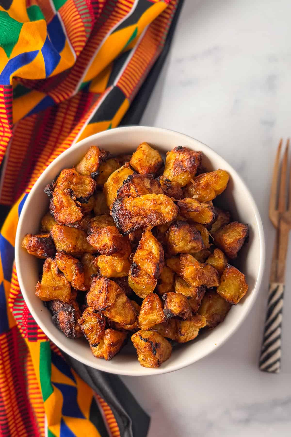 A bowl of air fryer kelewele with a fork on the side.