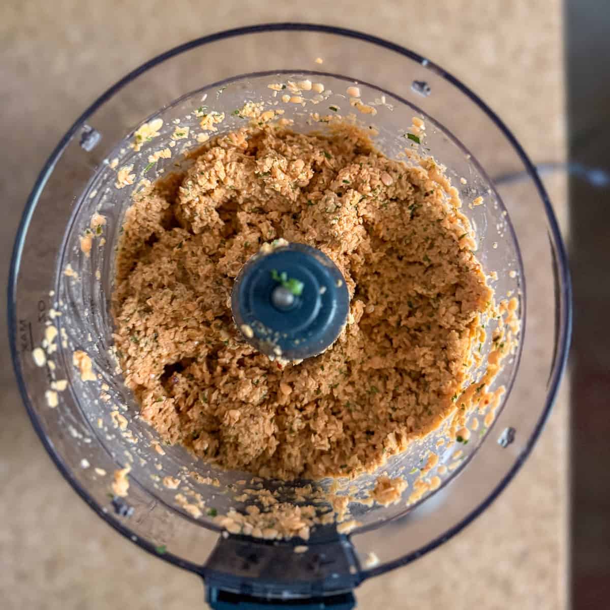 Red lentil mixture in a food processor after processing.