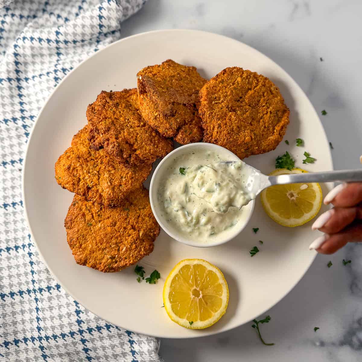 Red lentil fritters on a plate with dipping sauce.
