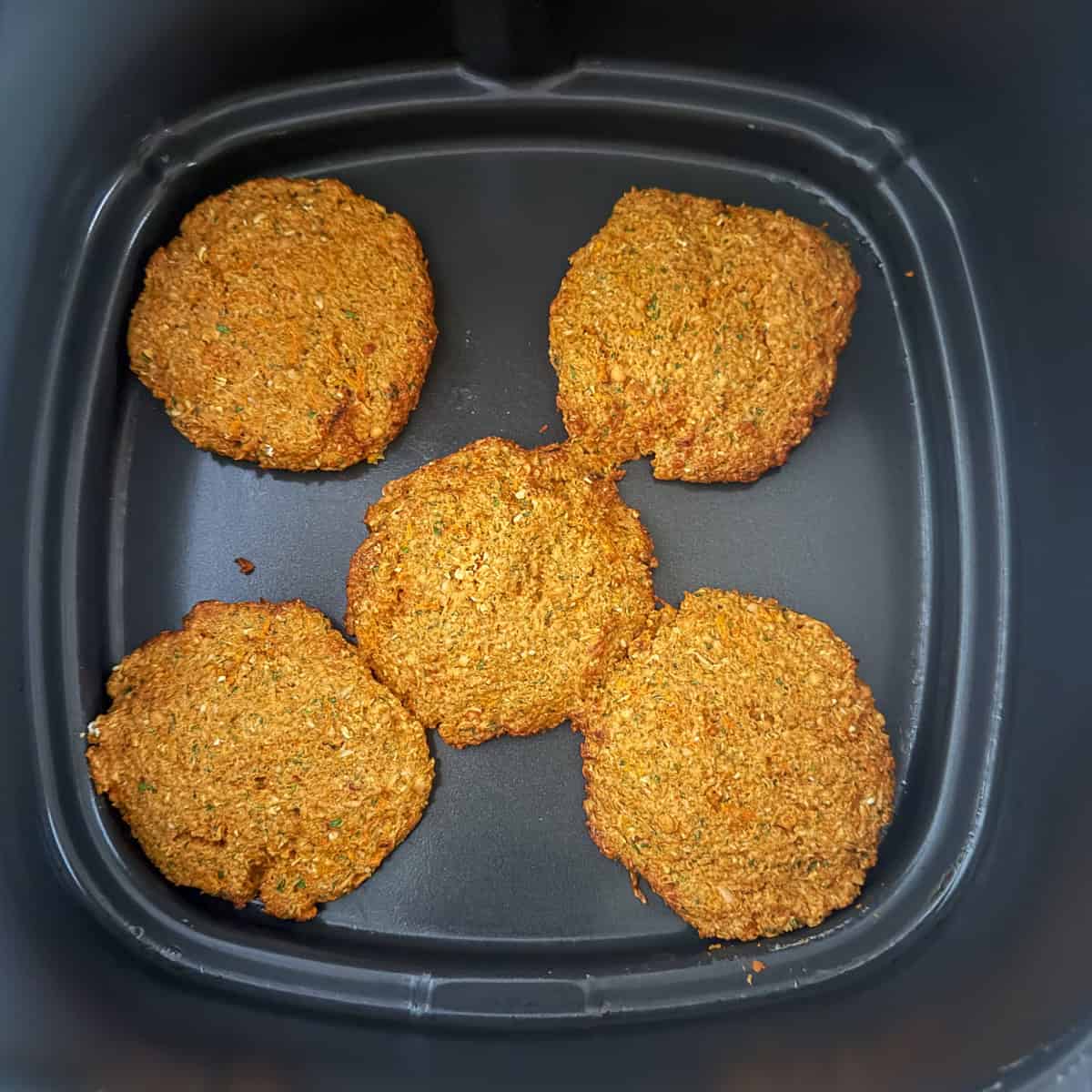 Red lentil fritter patties in the air fryer basket.
