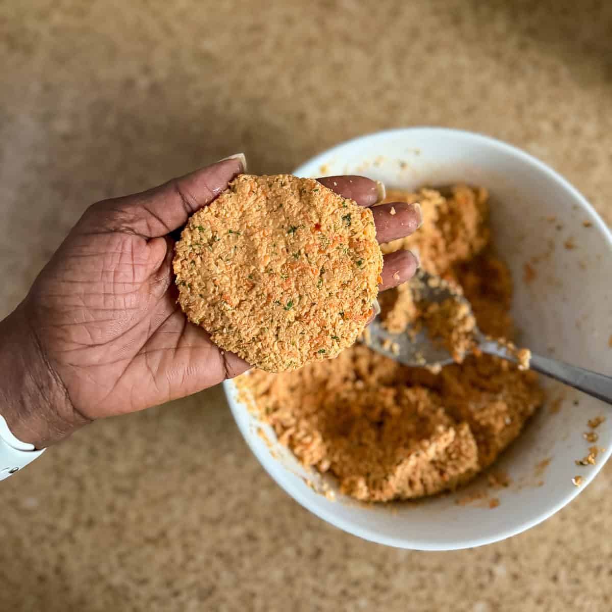 A woman's hand forming the red lentil fritter patties.