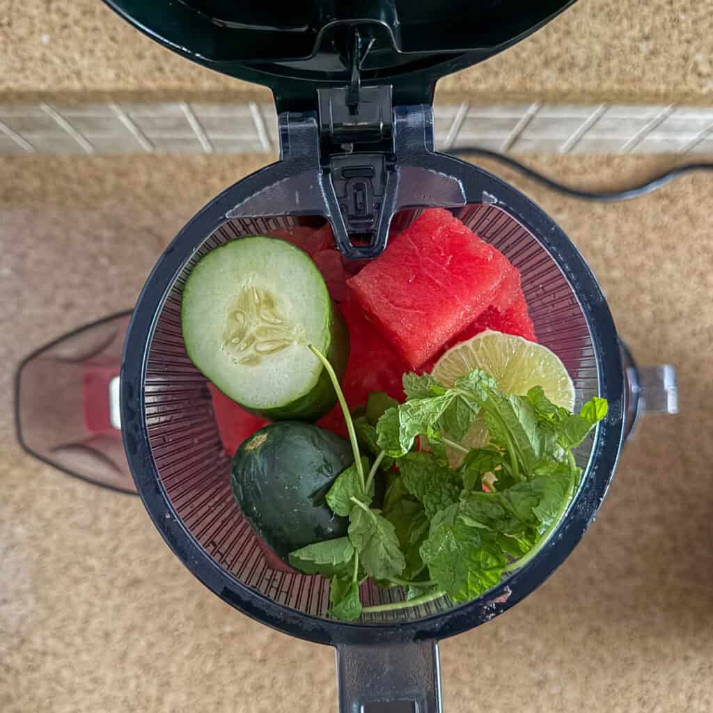 Watermelon, lime, cucumber and mint in the juicer shoot container before juicing.