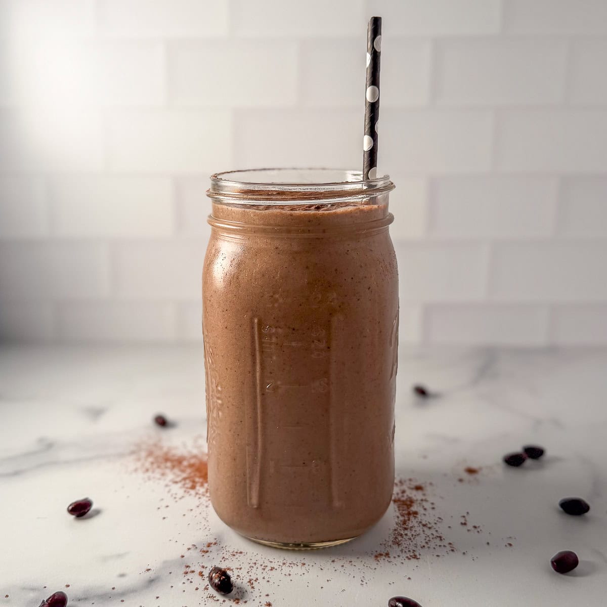 A frosty chocolate black bean smoothie in a large mason jar with a straw.