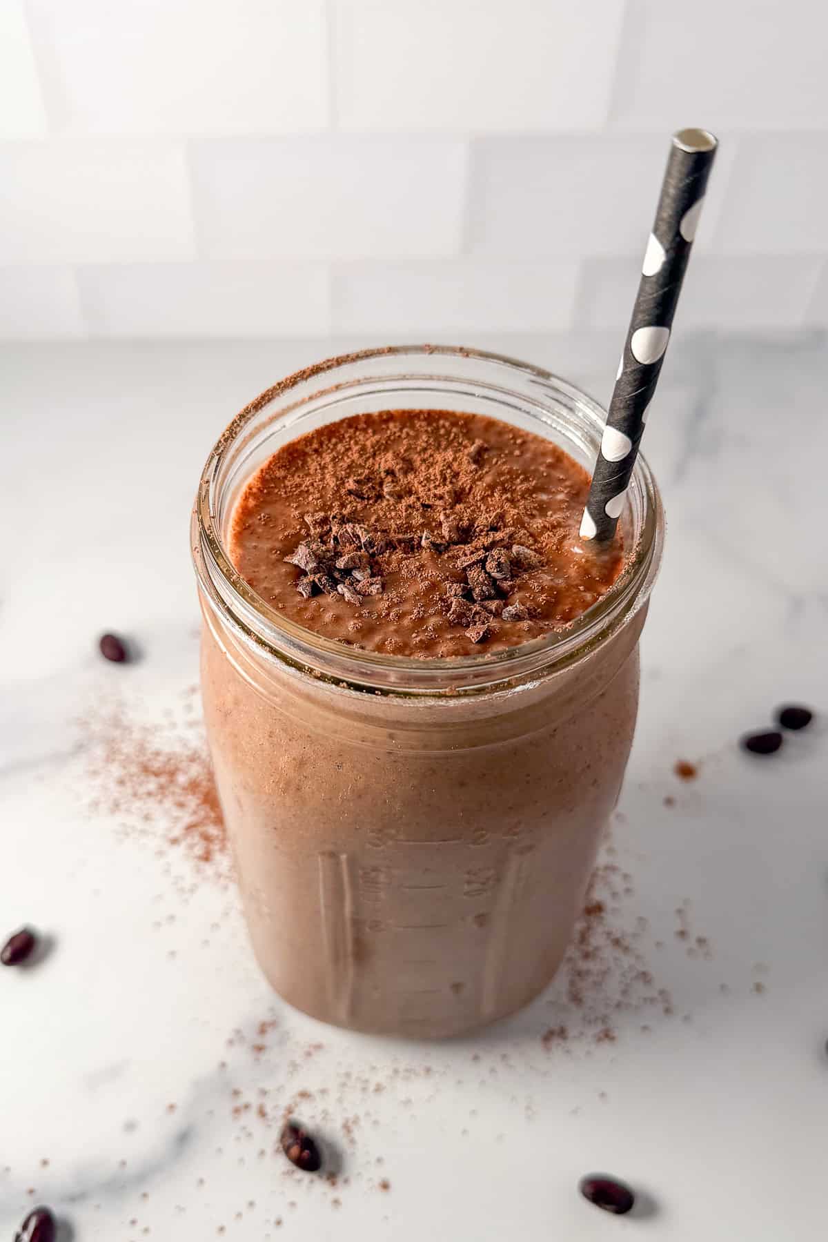 A frosty chocolate black bean smoothie in a mason jar with a straw.