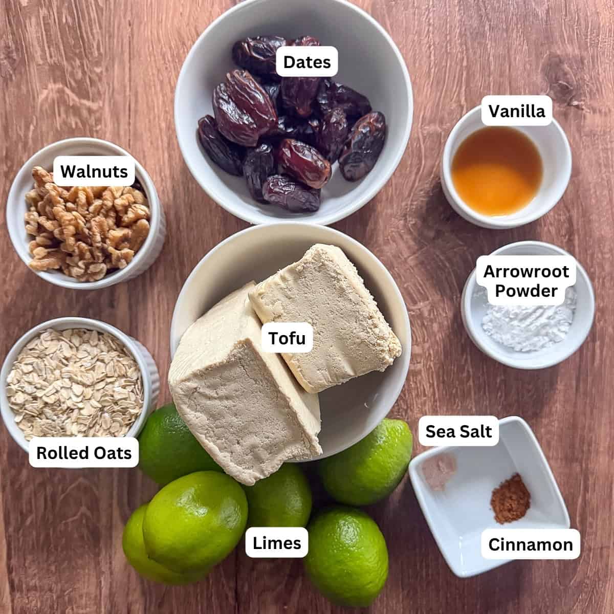 Ingredients for vegan lime pie: dates, tofu, walnuts, rolled oats, limes, vanilla extract, arrowroot powder, sea salt, and cinnamon.
