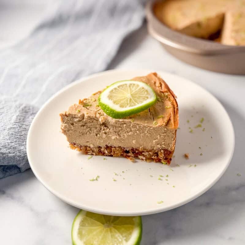 A slice of vegan lime pie on a plate with lime on top.