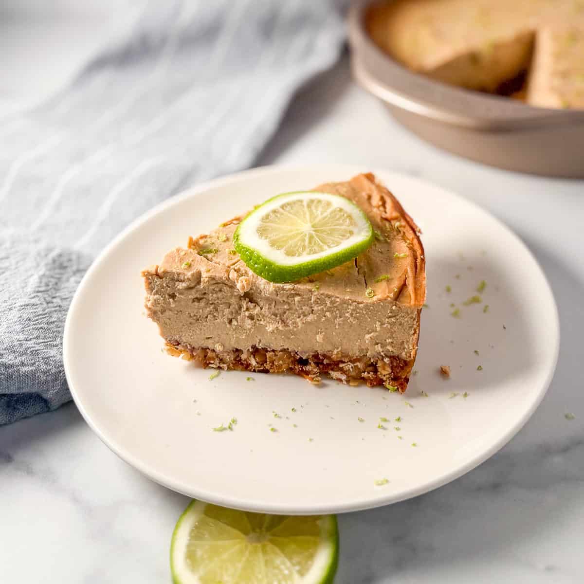 A slice of vegan lime pie on a plate with lime on top.