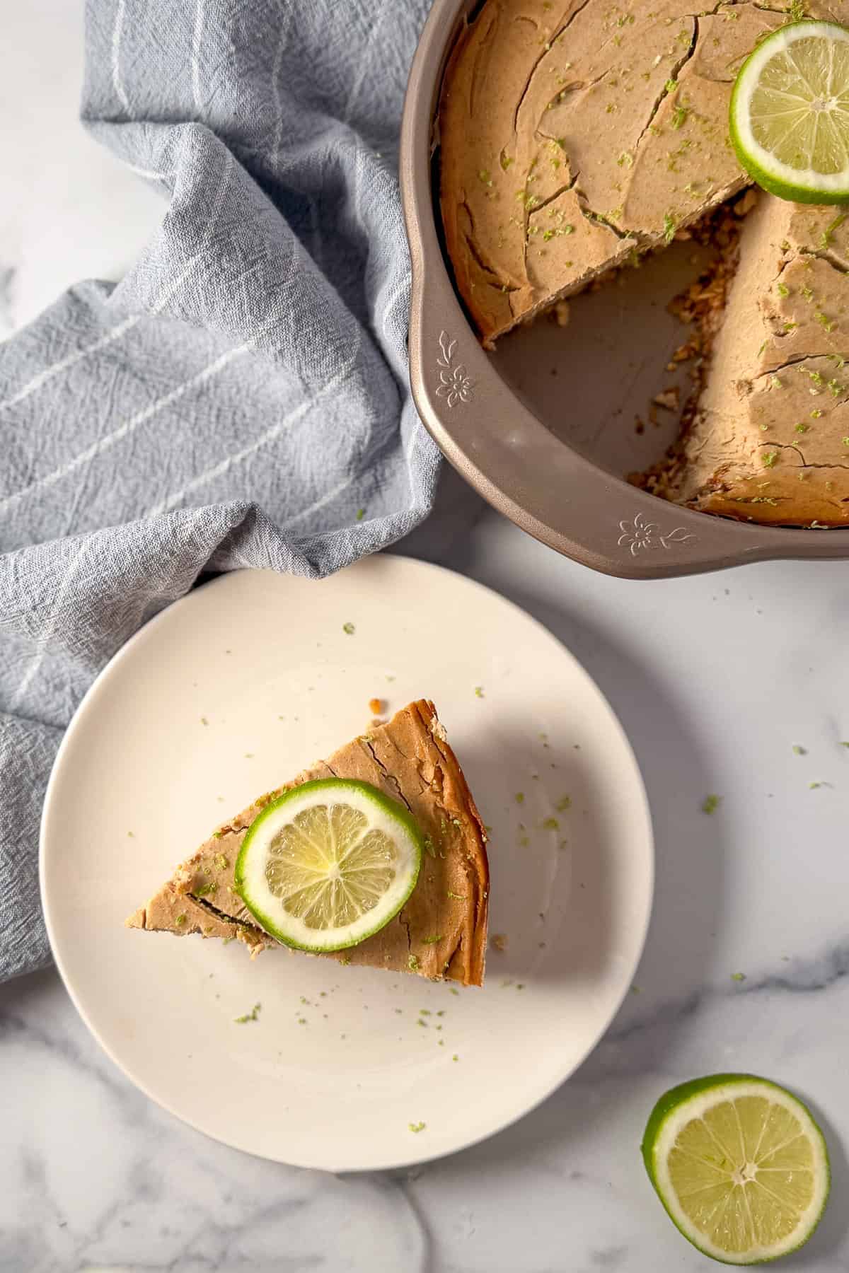 A slice of vegan lime pie on a plate with fresh lime slice on top.