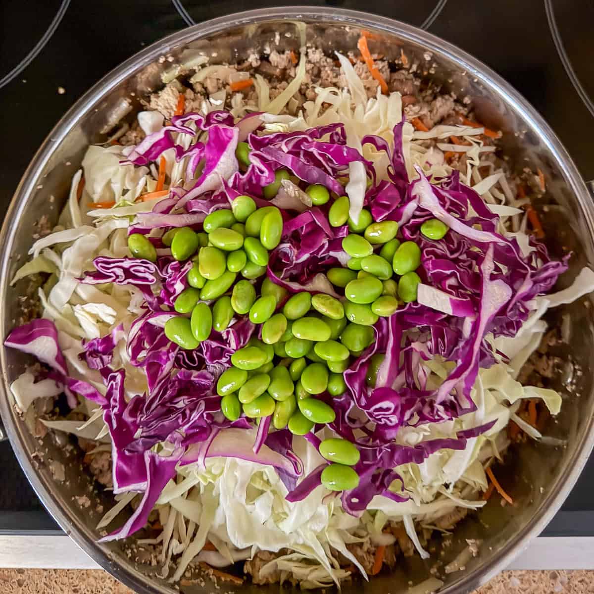 Cabbage and edamame added to the large sauté pan with tofu and other veggies.