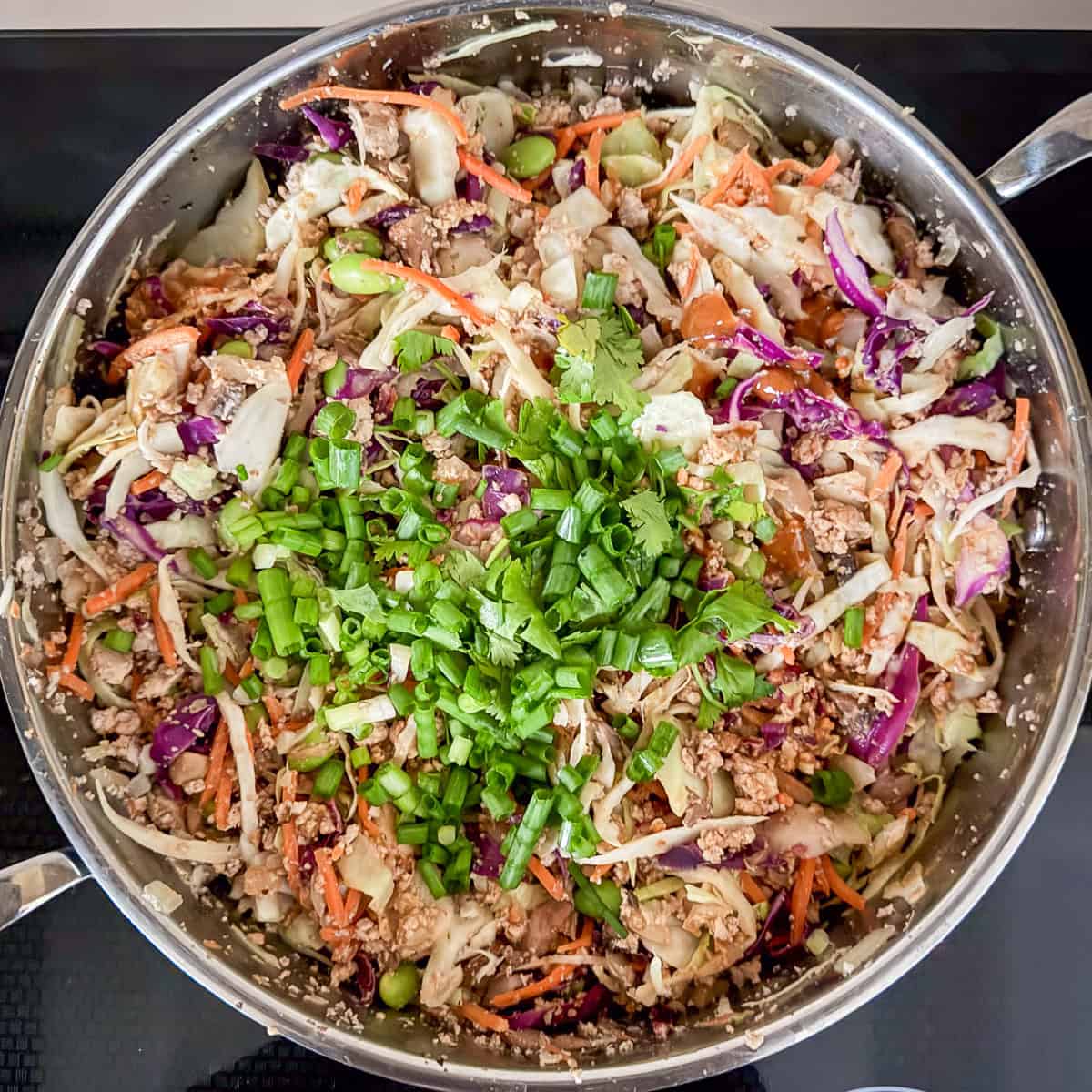Cilantro and green onion added to the vegan egg roll mixture in the pan.